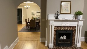 A dining area with a fireplace, wooden flooring, and a chandelier. - Close to Downtown & UWEC (Eau Claire)