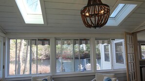 A room with a large window overlooking a body of water, a ceiling fan, and two armchairs with decorative pillows. -  Cozy Waterfront cottage with Private dock- dog friendly!   (Lyman)