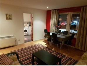 Cozy living area with a dining table for four, comfortable chairs, and a large window offering a view of the outside.