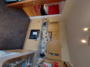 Compact kitchen with central island, sink, stove, microwave, and range hood.