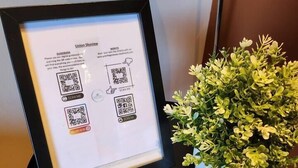 Un poster Union Skyview incorniciato con codici QR, un telecomando e una pianta in vaso su un tavolo.