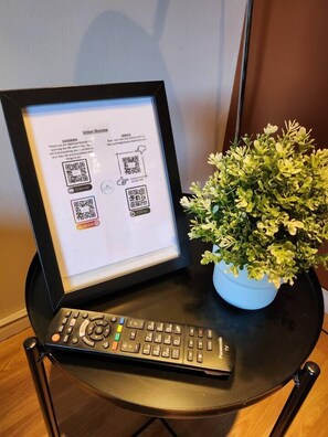Une affiche encadrée de la série Union Skyview, dotée de codes QR, une télécommande et une plante en pot, le tout posé sur une table.