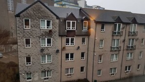 Un edificio residenziale a più piani con facciata in pietra, diverse finestre e balconi.