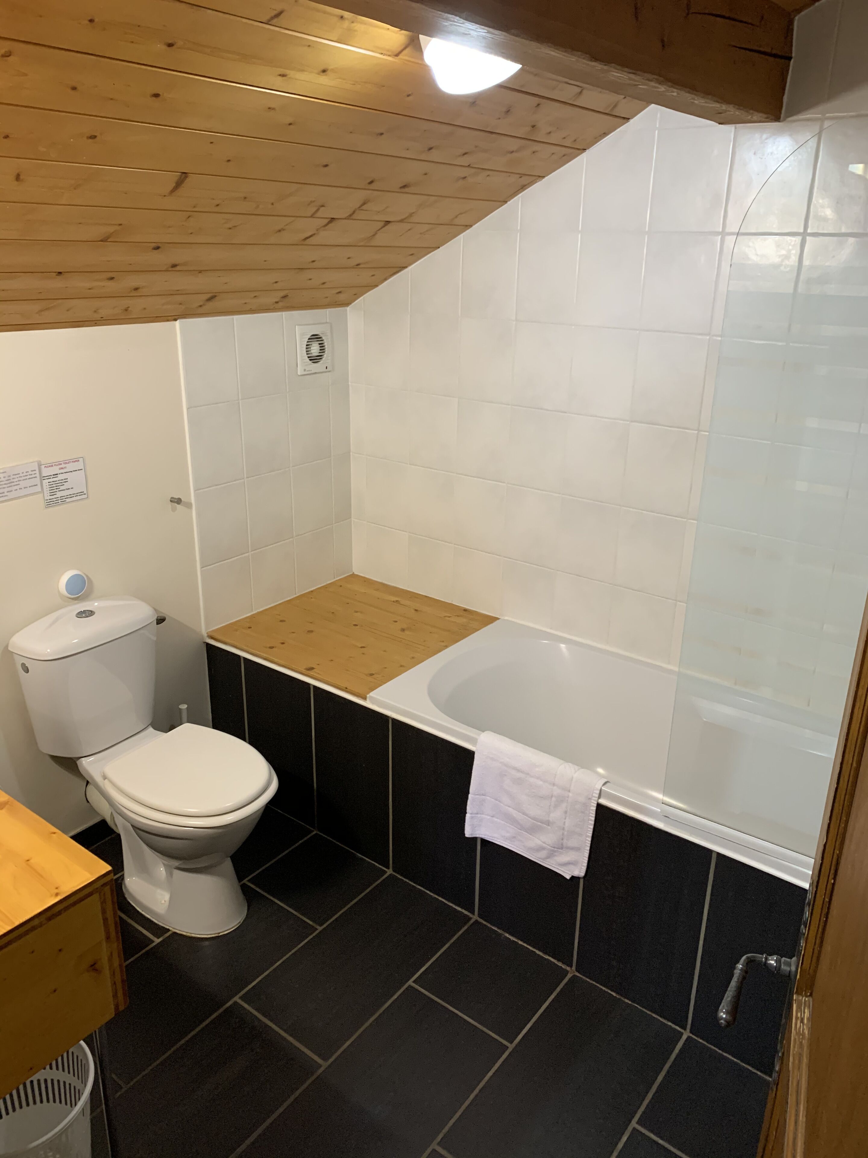 Un baño con inodoro, bañera y tocador de madera.