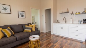 A living room with a grey sofa, yellow cushions, and a small round table with a remote control. - Top floor upscale contemporary space with great views and great location (Galveston)