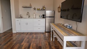 A compact kitchen with white cabinets, a stainless steel refrigerator, and a wooden table. - Top floor upscale contemporary space with great views and great location (Galveston)