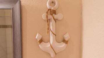 Une décoration en forme d’ancre blanche, ornée d’une corde, sur un mur de couleur beige.