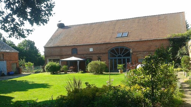 Ein Backsteinhaus mit einem großen Bogenfenster und einer überdachten Außenbestuhlung.