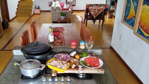 A kitchen with a stove, pots, and various food items on the counter.