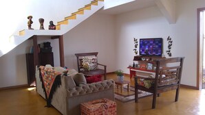 A living room with a sofa, a coffee table, a TV, and a staircase.