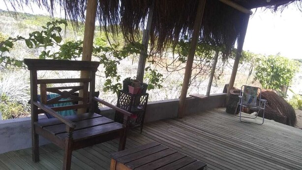 A wooden deck with a thatched roof, a wooden bench, and a small table.