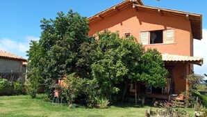 A two-story house with a tiled roof, surrounded by a well-maintained garden with various plants and a lawn.