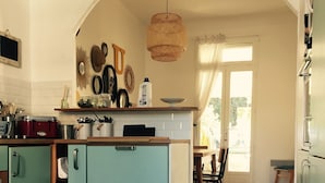Una cocina con gabinetes verde azulado, una lámpara colgante y piso de baldosas.