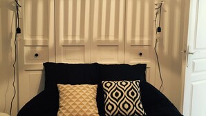 Un dormitorio con cama, dos lámparas de noche, un aplique colgante y una puerta blanca.