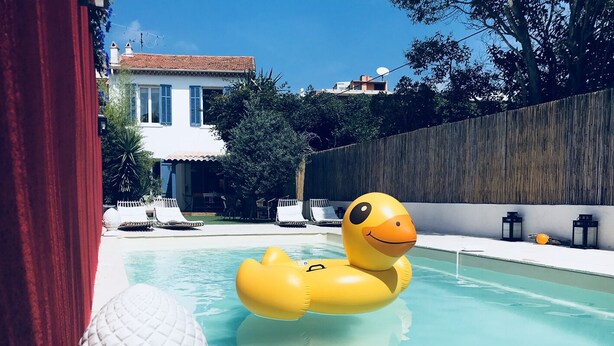 Una piscina con un patito inflable amarillo, sillas de descanso y una esfera decorativa blanca.