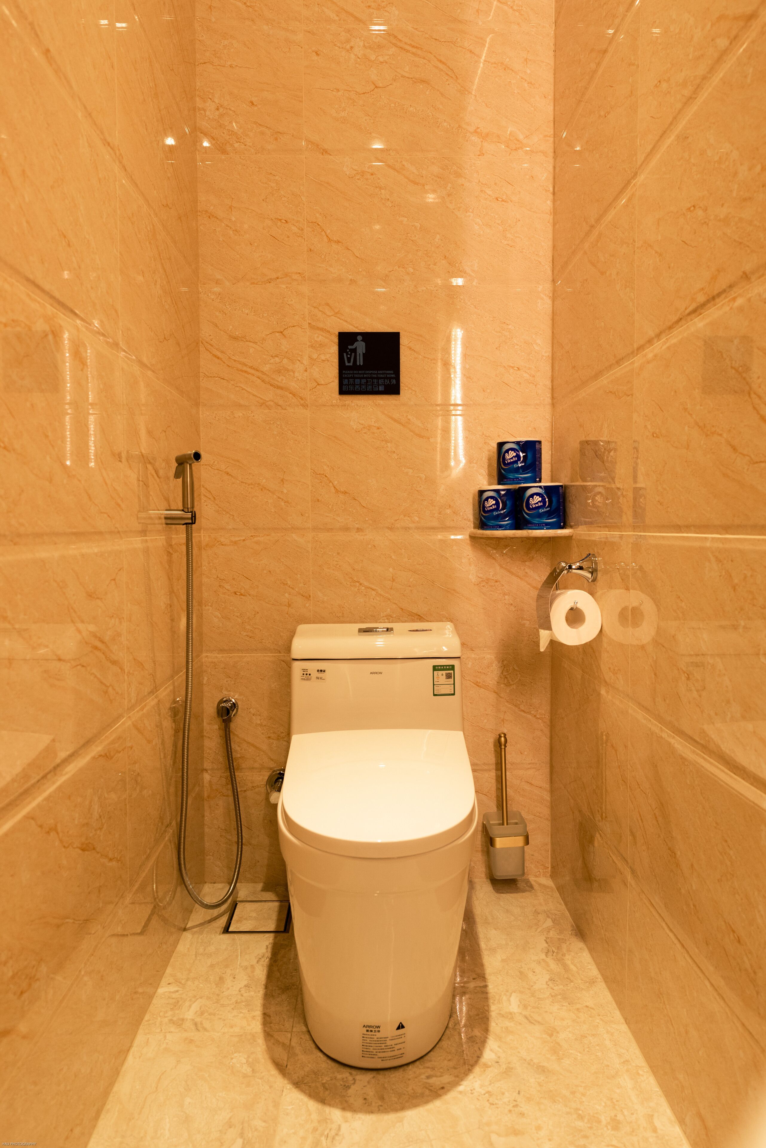 Ein kleines Badezimmer mit Toilette, Dusche und Toilettenpapierhalter.