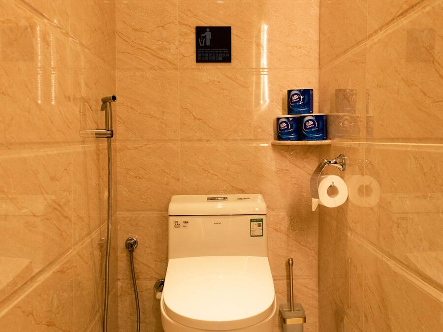 Ein kleines Badezimmer mit Toilette, Dusche und Toilettenpapierhalter.