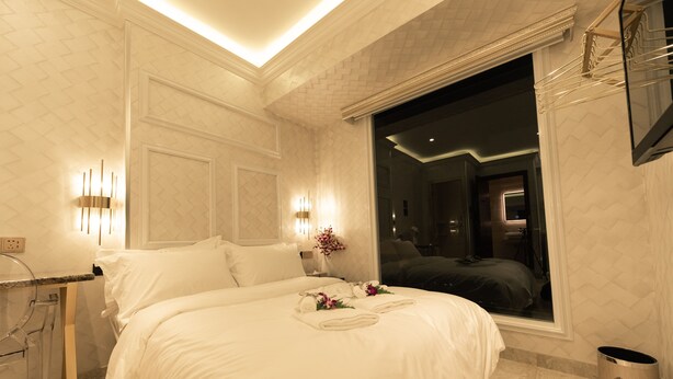 Habitación de hotel moderna con una cama grande, una mesita de noche, un espejo y una ventana con vistas al interior.
