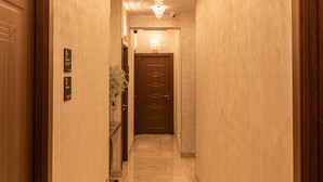 Un pasillo de hotel con suelo de mármol, puertas de madera y un candelabro.