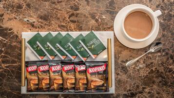 A tray with Kopiko coffee packets and a cup of coffee on a marble surface.