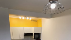 A compact kitchen with white cabinets, a microwave, and a coffee maker on the counter. - Renovated one-bedroom apartment, 300 m from the beach, free private parking (Bénodet)