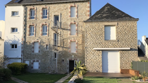 A two-story stone building with a spiral staircase, a garage, and a well-maintained lawn. - Renovated one-bedroom apartment, 300 m from the beach, free private parking (Bénodet)