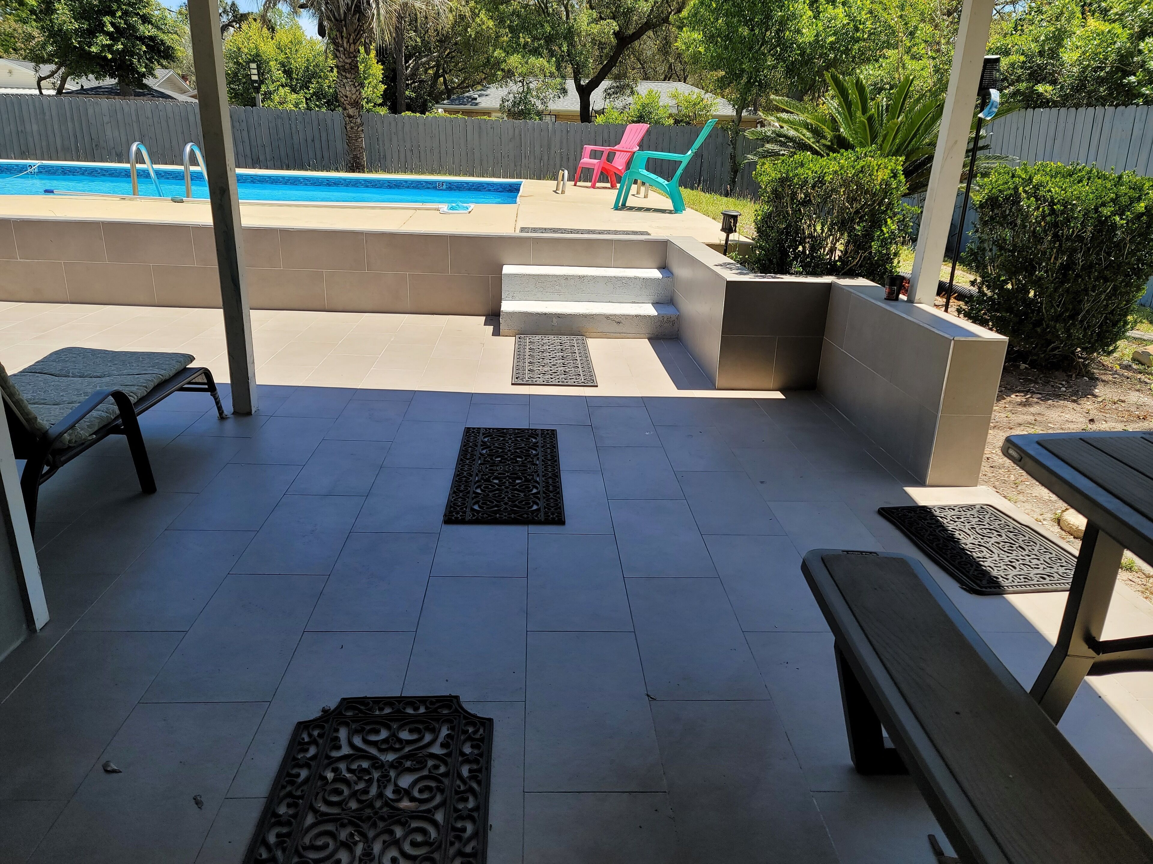 Un espace patio avec une piscine, du mobilier d’extérieur et une clôture en bois.