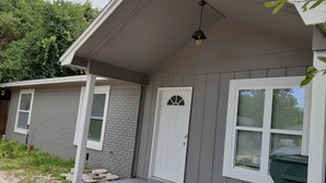 Een woonhuis met een overdekte veranda, een bakstenen gevel en een witte deur.