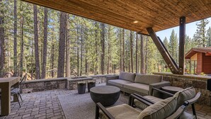 Un patio esterno con pavimento in pietra, mobili in legno e vista su una foresta.