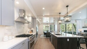 Una cucina moderna con isola centrale, elettrodomestici in acciaio inossidabile e illuminazione a sospensione.