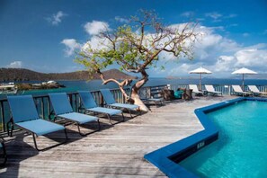 A wooden deck with blue lounge chairs and a swimming pool.