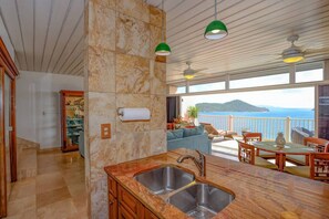 Uma cozinha moderna com bancada de mármore, uma pia e vista para o mar.