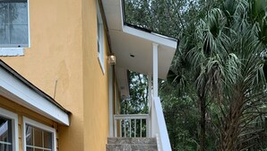 A staircase leading to a porch with a yellow exterior wall and stone steps.