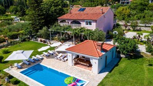 Una casa con piscina, tumbonas y jardín.