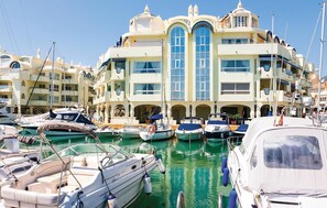 A marina with multiple boats docked in front of a large, multi-story building with arched windows and balconies. - Stunning home in Benalmadena Costa (Benalmadena Costa)