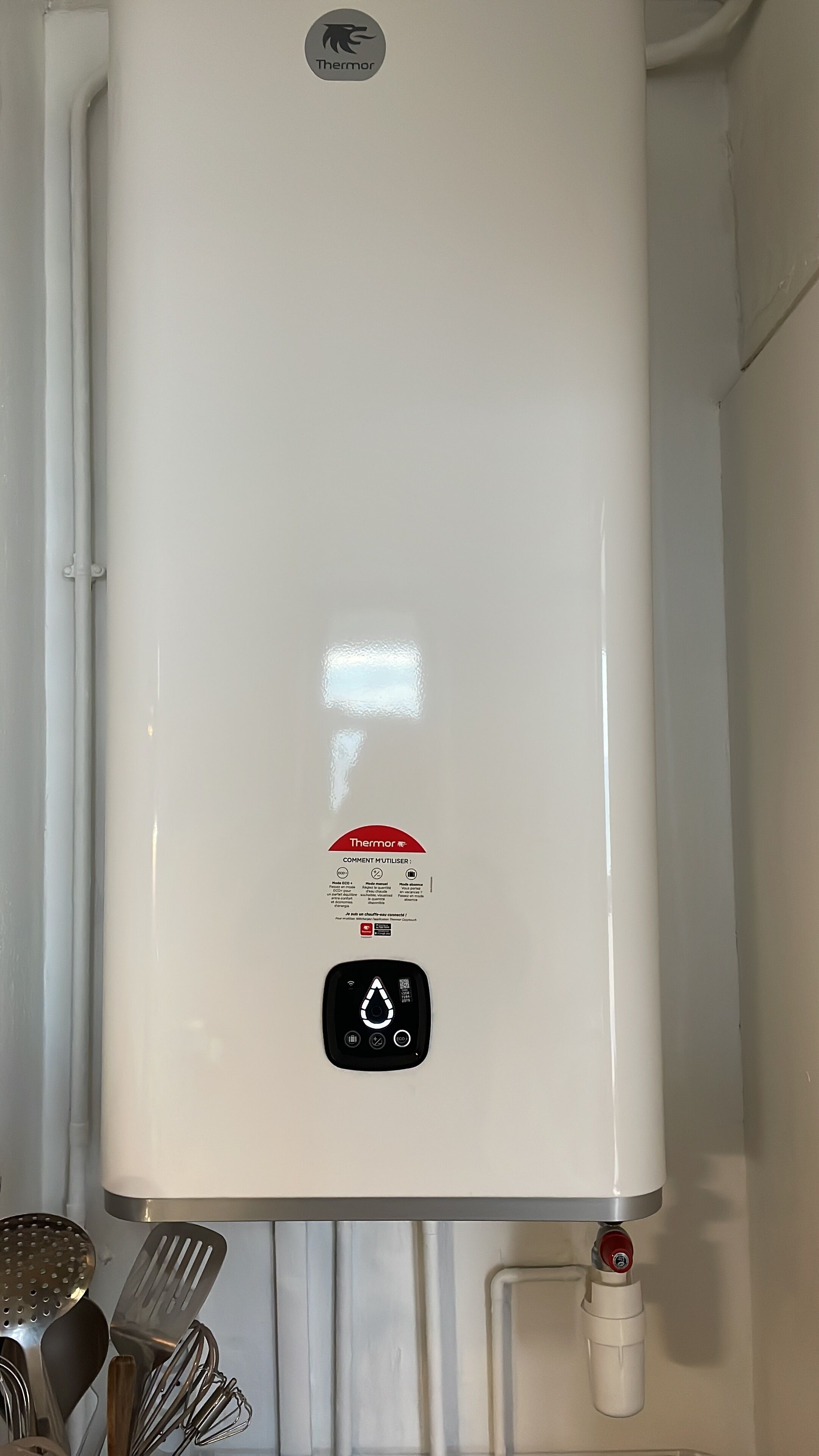 A white water heater with a control panel and a red safety label.