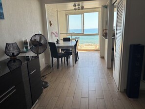 Un espace repas avec vue sur la plage, un ventilateur et un haut-parleur.