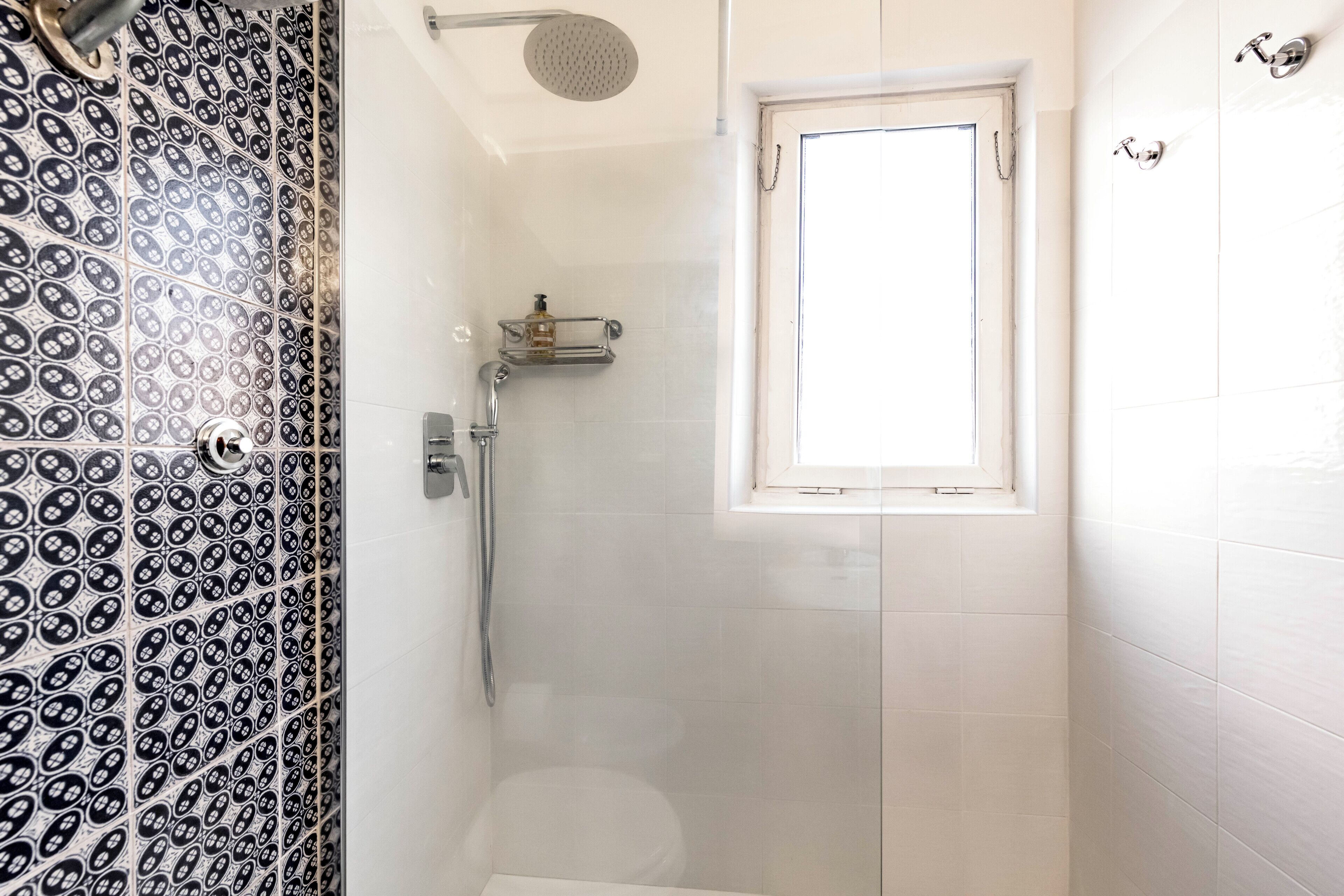 Ein Badezimmer mit Dusche, Toilette und Fenster.