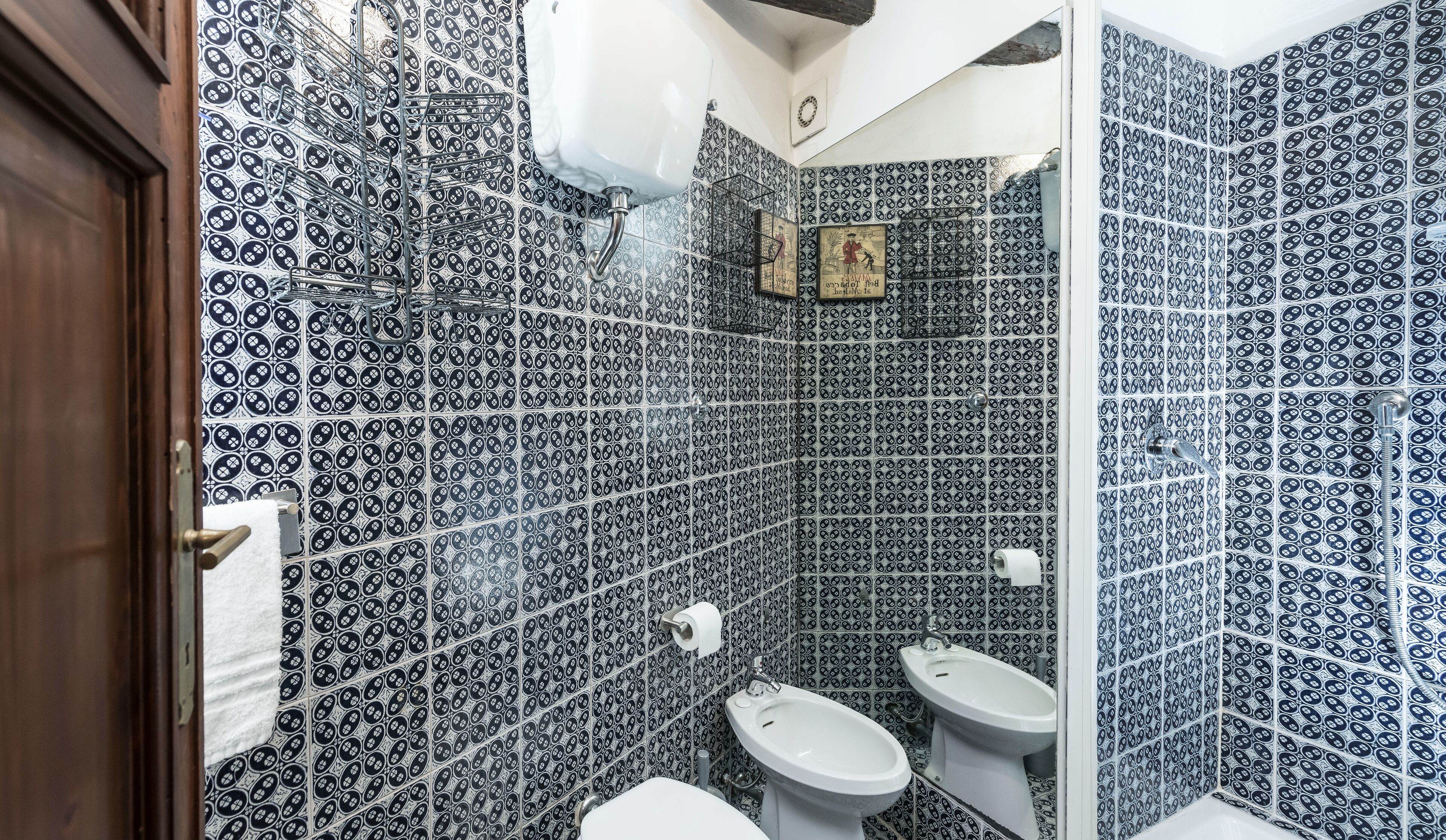A bathroom with patterned tiles, a toilet, a bidet, and a shower area.