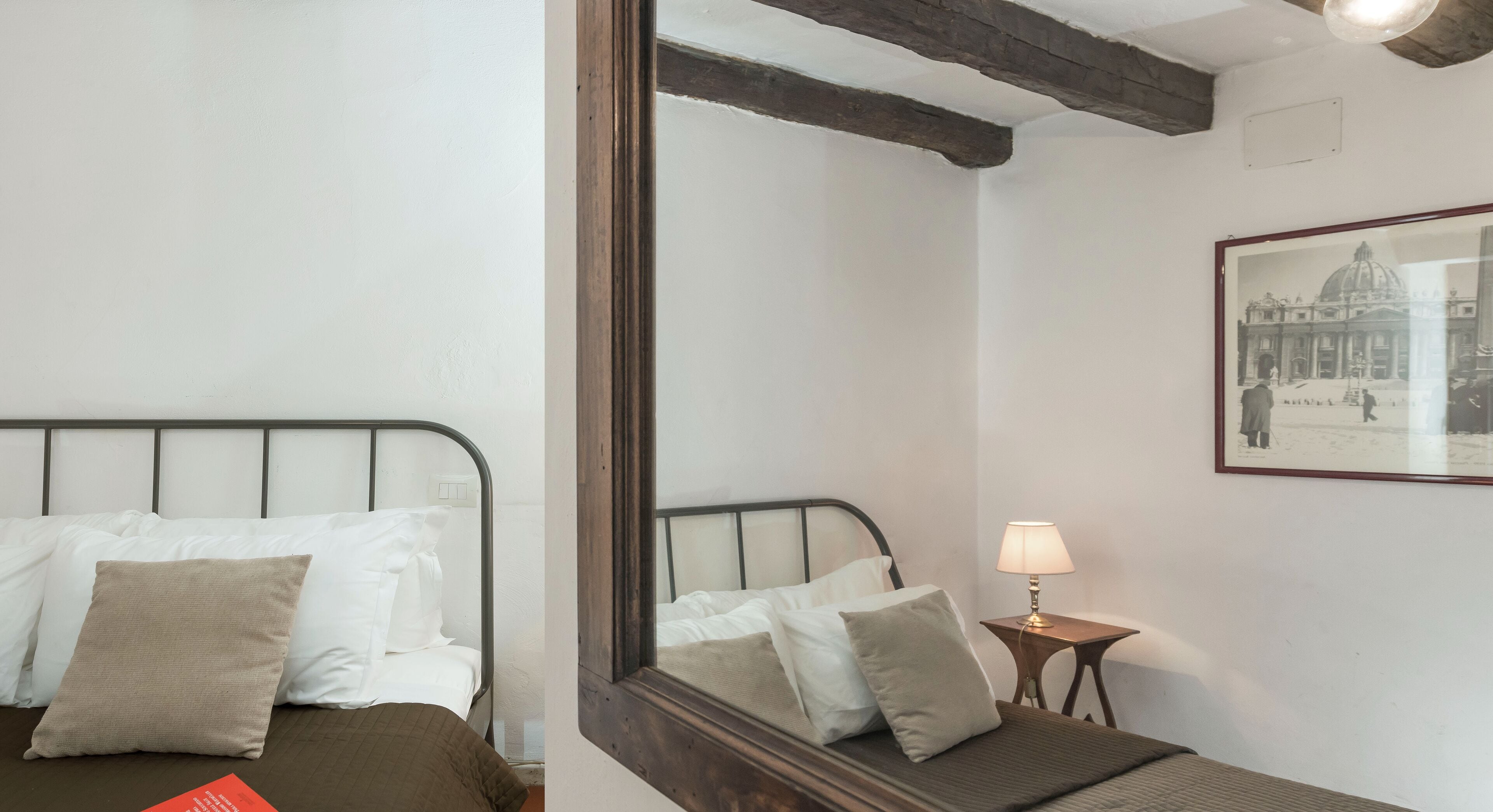 A bedroom with a bed, pillows, a bedside table with a lamp, and a framed picture on the wall.