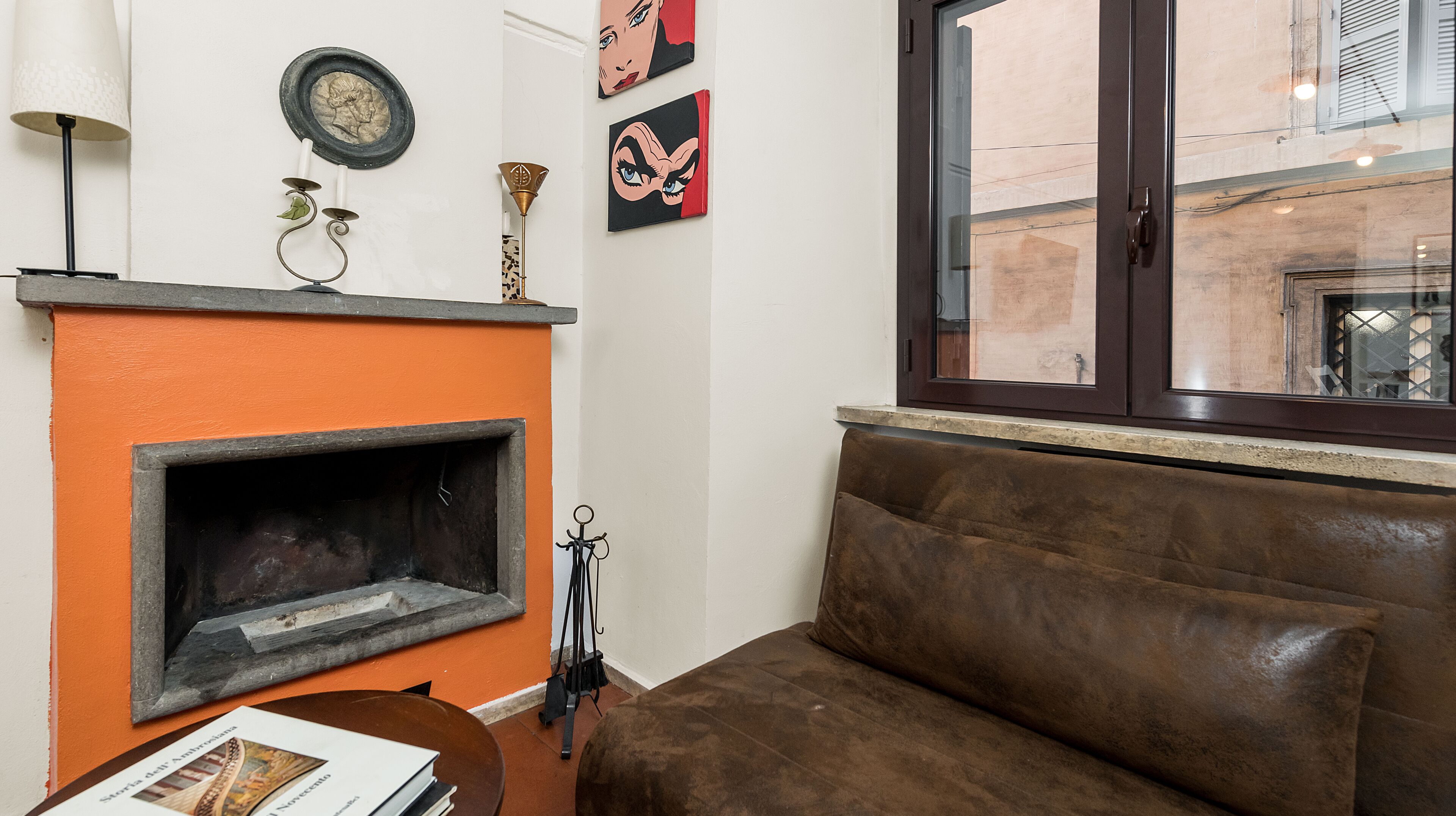 A living room with a fireplace, a brown sofa, and artwork on the wall.