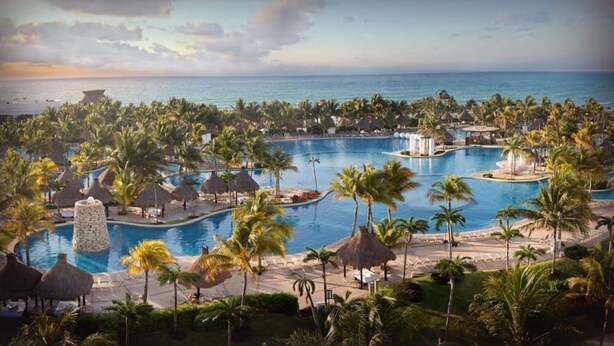 Un complexe hôtelier doté de plusieurs piscines, de palmiers et offrant une vue sur la plage.