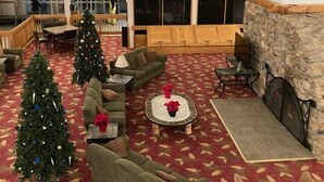 Un hall d’entrée spacieux avec une cheminée, plusieurs coins salon et des sapins de Noël.