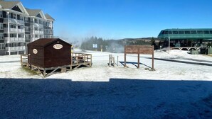 Une cabane en bois, avec une pancarte, un banc et un sol recouvert de neige.