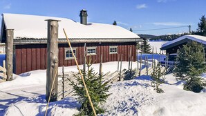 A wooden cabin with a snow-covered roof, a chimney, and a small porch area. - Awesome home in Sjusjøen with WiFi (Sjusjøen)