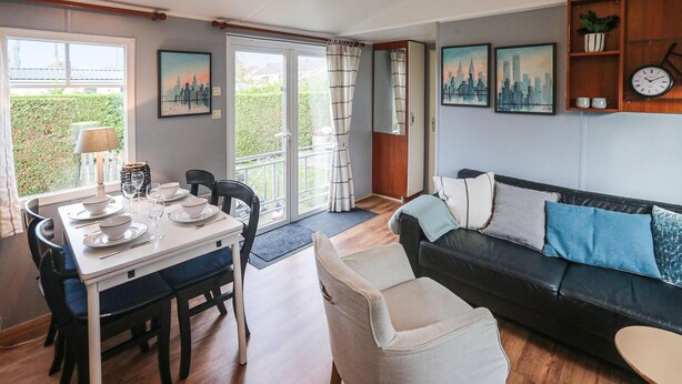 Un coin repas avec une table dressée pour quatre personnes, un canapé et une petite table avec une lampe.