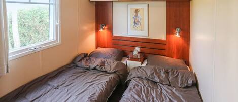 A small bedroom with two single beds, a bedside table with a lamp, and a framed picture on the wall.