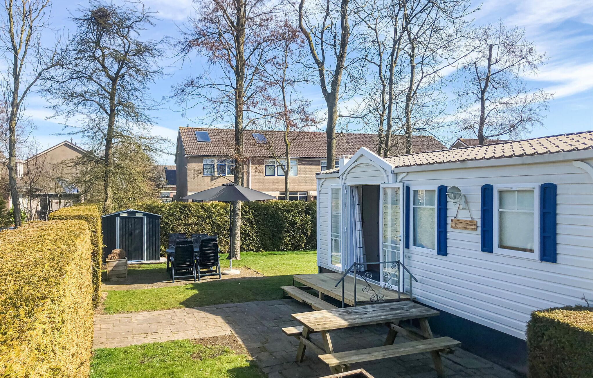 A mobile home with a patio area, a small shed, and a lawn.