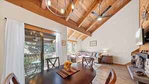 Un comedor amplio con una mesa y sillas de madera, un balcón con puertas de vidrio y una cocina con detalles de piedra.