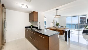 A modern kitchen with a central island, a dining area with a view, and a large window. - ICON W BRICKELL AMAZING OCEAN VIEW 2BR/1BA (Miami)